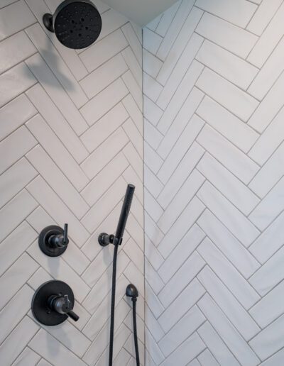 A shower with herringbone tile and a shower head.