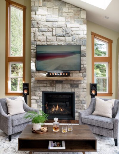 A living room with a stone fireplace and a flat screen tv.