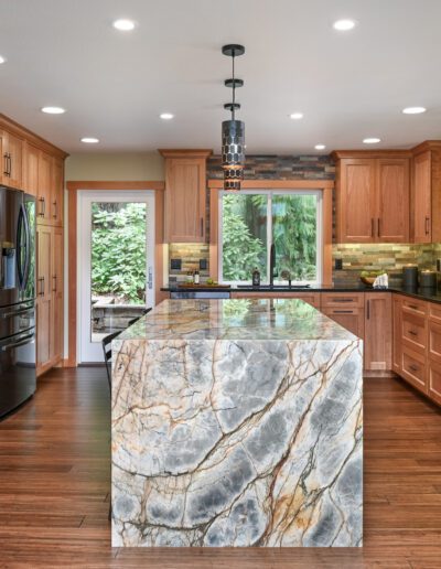 A kitchen with wood cabinets and marble counter tops.