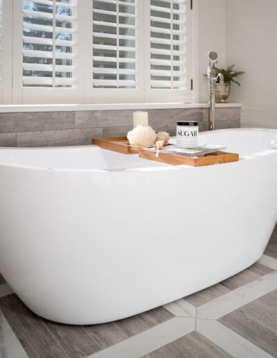 A white bathtub in a bathroom with wooden shutters.