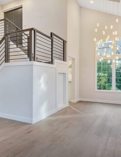 An empty living room with wooden floors and a staircase.