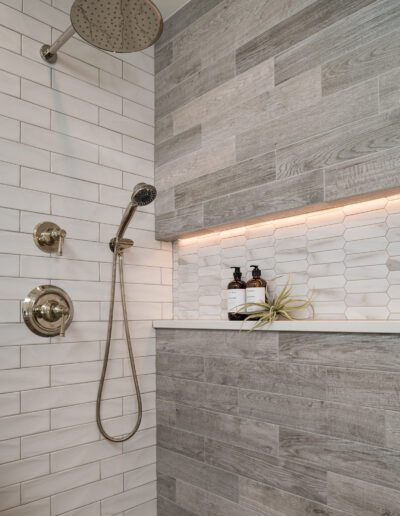 A white tiled shower with a shower head and shower head.