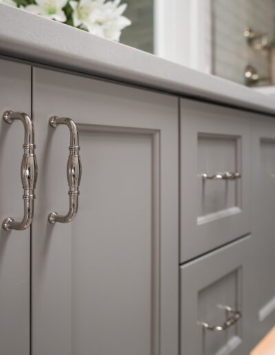 A bathroom with gray cabinets and a white sink.