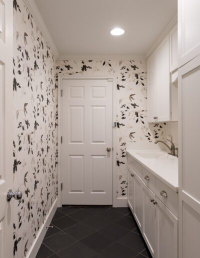 A white laundry room with black and white wallpaper.