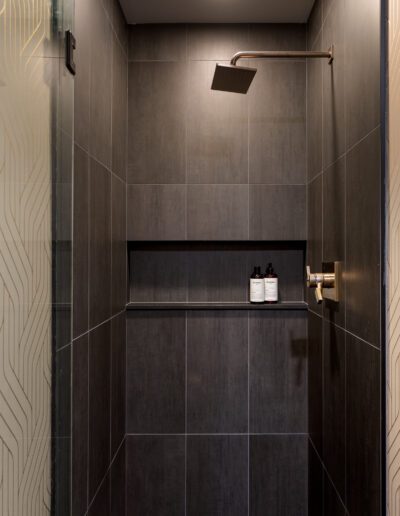 A black tiled shower with a glass door.