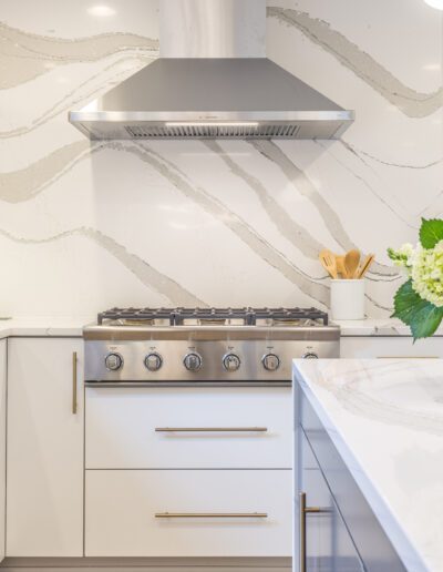 A white kitchen with marble counter tops.