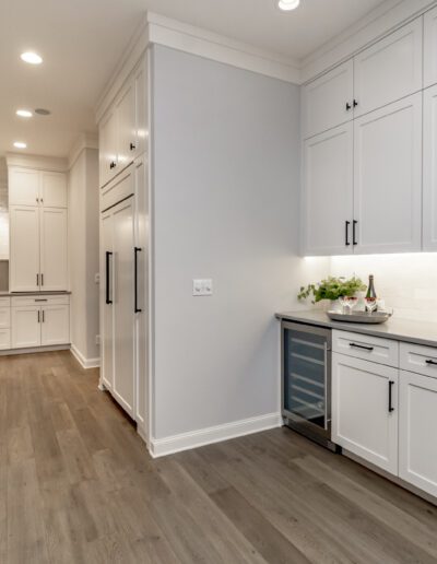 A kitchen with white cabinets and hardwood floors.