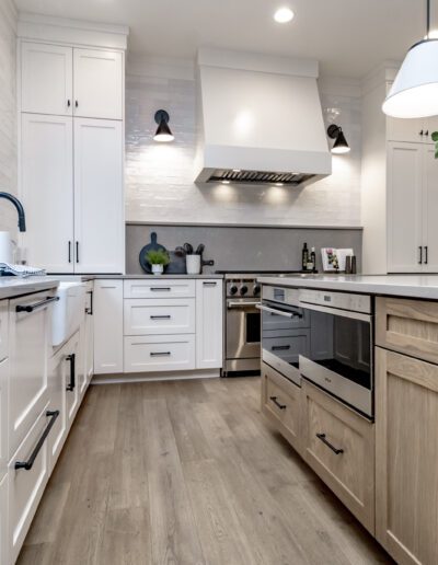 A kitchen with white cabinets and wood floors.