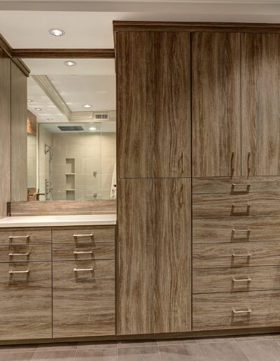 A walk in closet with wooden cabinets and a mirror.