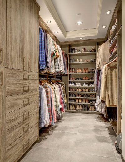 A walk in closet with a lot of clothes and shoes.