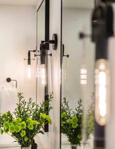 A bathroom with a mirror and a vase of flowers.