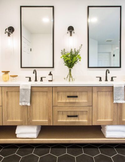 A bathroom with a black hexagon tile floor and wooden vanity.