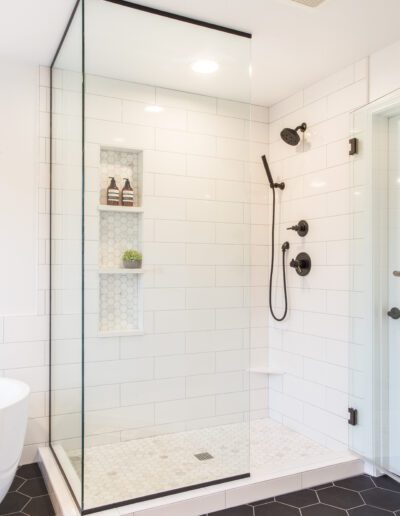 A white and black bathroom with a glass shower stall.