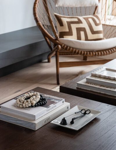 A living room with a wicker chair and books on a table.