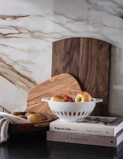 A bowl of apples, a bowl of bread, and a book on a counter.