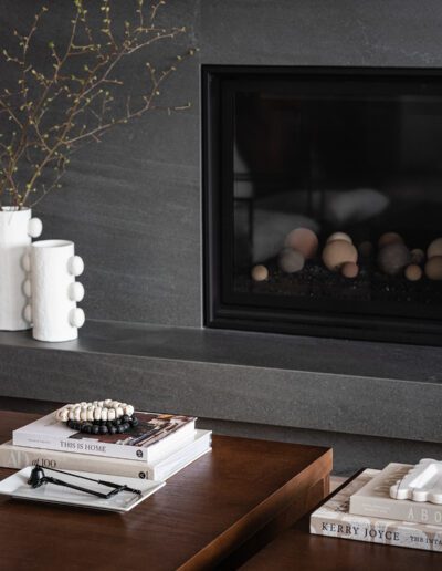 A living room with a fireplace and books on a table.