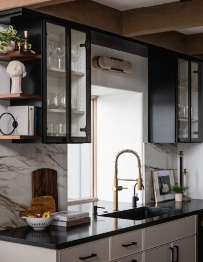 A black and gold kitchen with a wooden counter top.