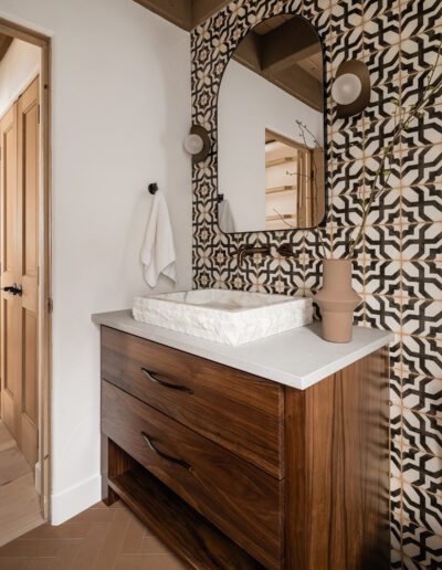 A bathroom with a wooden vanity and tiled walls.