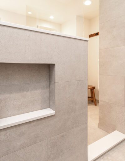 A bathroom with a white tiled wall and shelves.