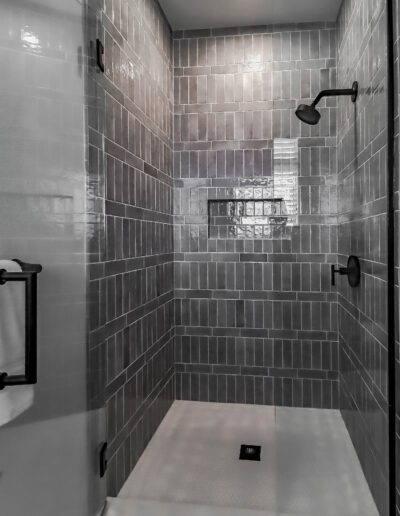 Modern bathroom featuring a glass-enclosed shower with gray tiles and black fixtures.