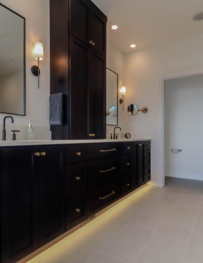 Modern bathroom with dual-sink vanity in black, white countertops, and mirrors; arch door leads to a tiled shower area.